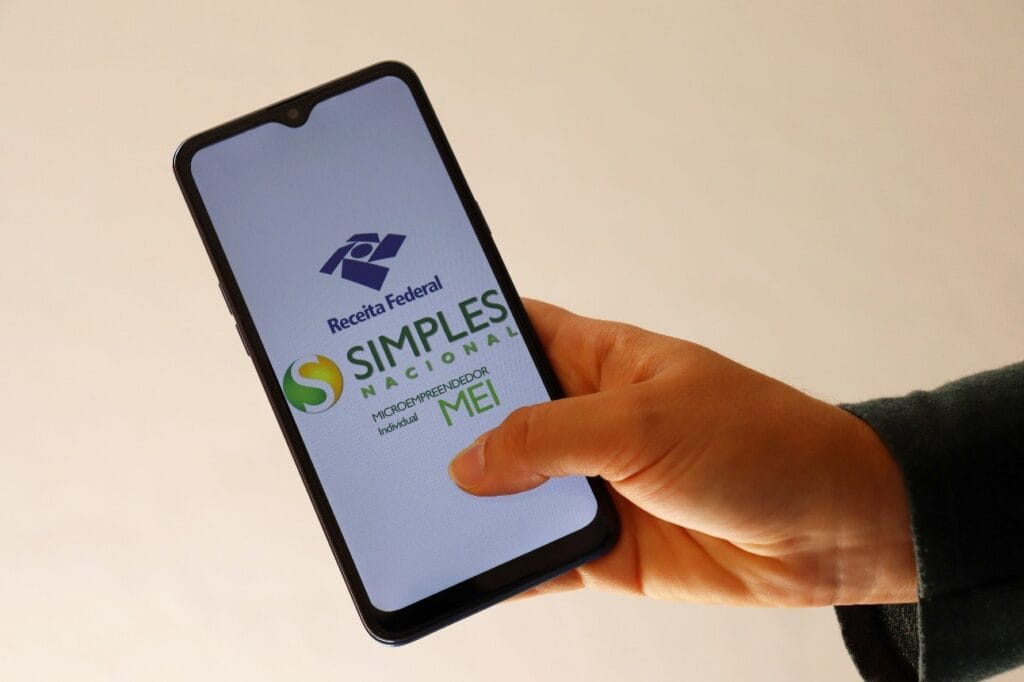 Guia Definitivo para Empreender em Casa em 2026: Modelos, Ferramentas e Estratégias 4 Close de uma pessoa preenchendo o formulário de cadastro do MEI em um smartphone, simbolizando a legalização de um negócio caseiro.